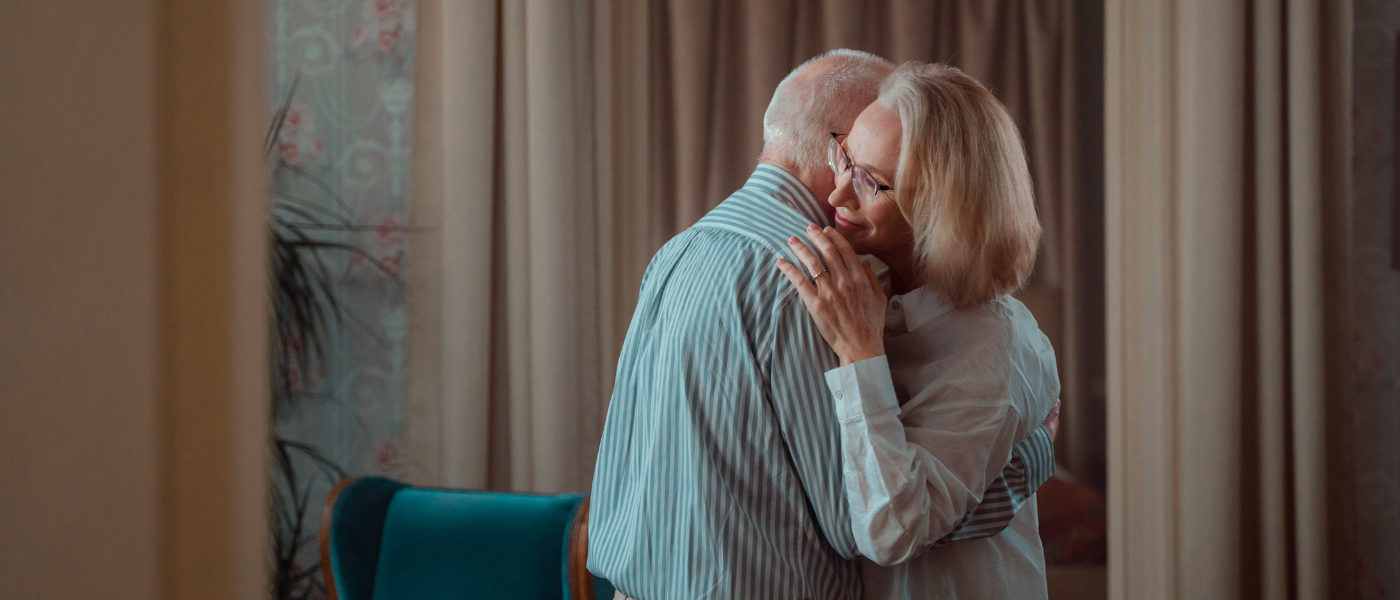 Elderly couple embrace in their home