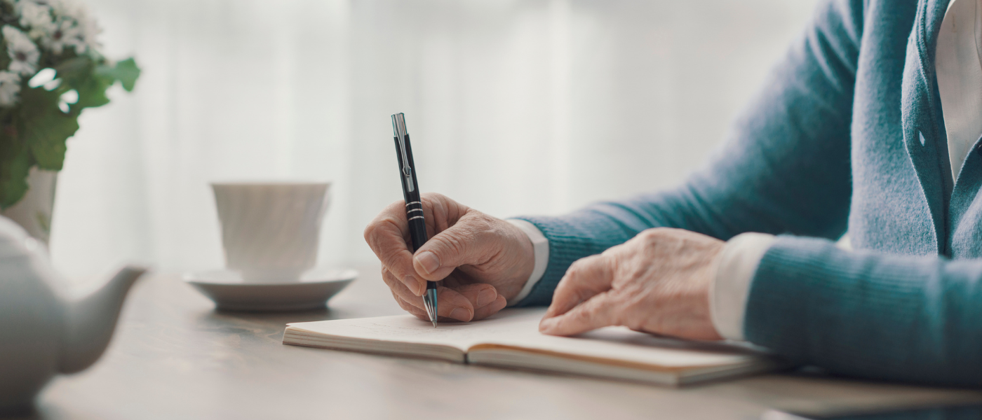 Older adult woman writing at a desk